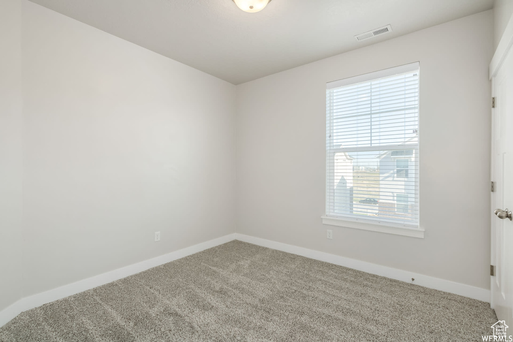 Carpeted spare room featuring baseboards