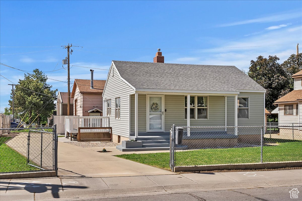 Bungalow-style house with a chimney, covered porch, and a fenced front yard