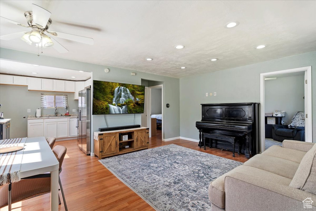 Living area with recessed lighting, light wood finished floors, and a ceiling fan