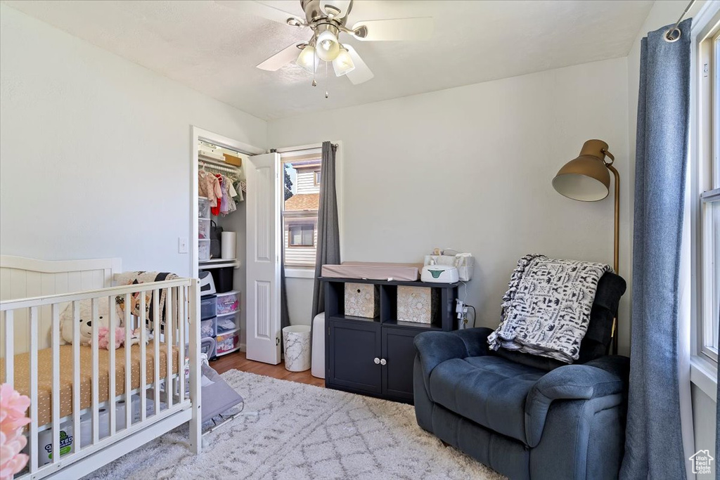 Bedroom featuring wood finished floors, ceiling fan, and a nursery area