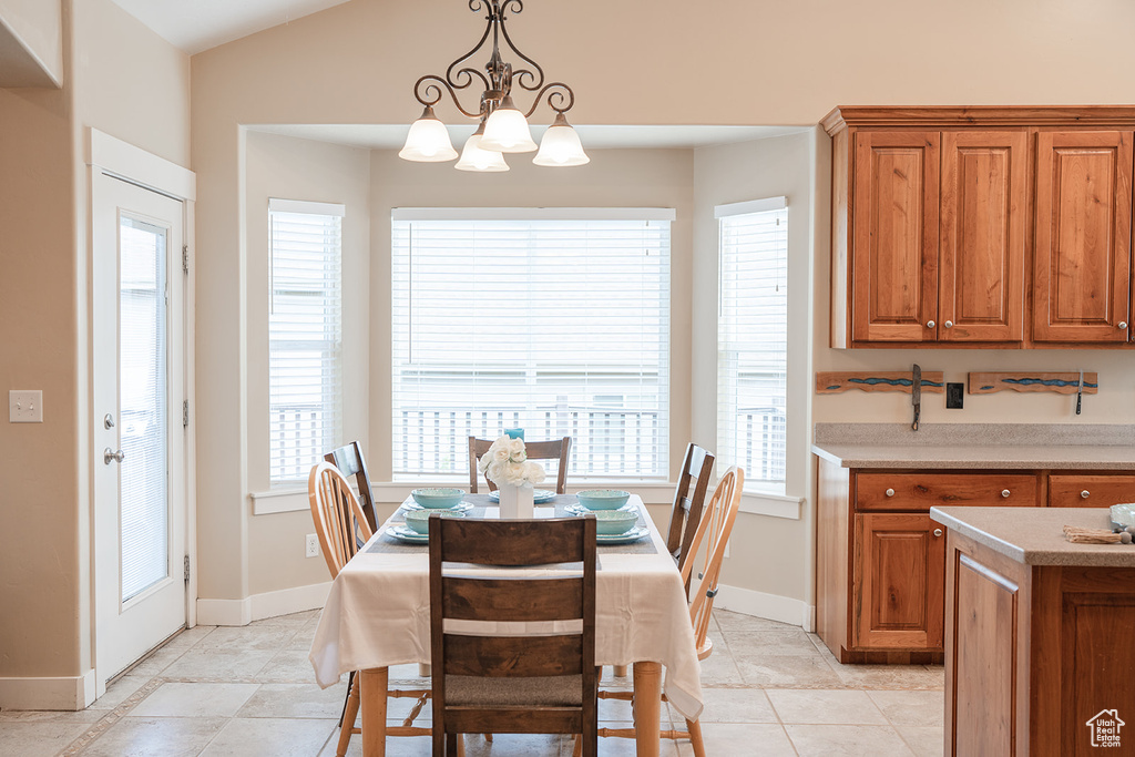 Dining space with a chandelier, light tile patterned flooring, baseboards, and vaulted ceiling