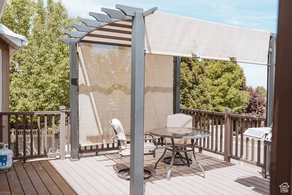 Wooden deck featuring outdoor dining area and a pergola
