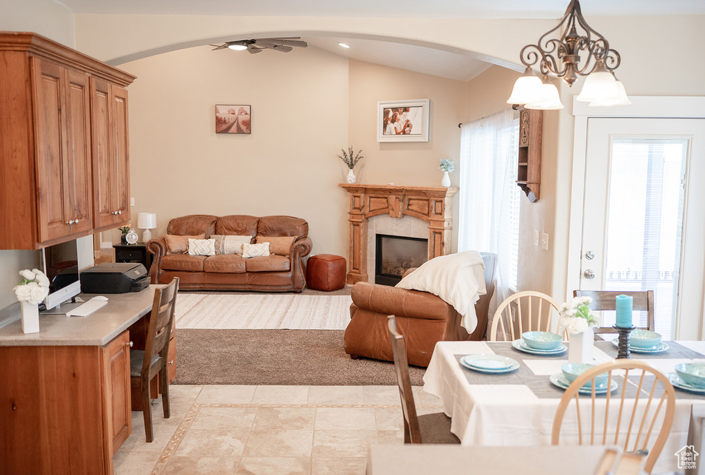 Living room featuring arched walkways, a high end fireplace, lofted ceiling, ceiling fan, and a chandelier