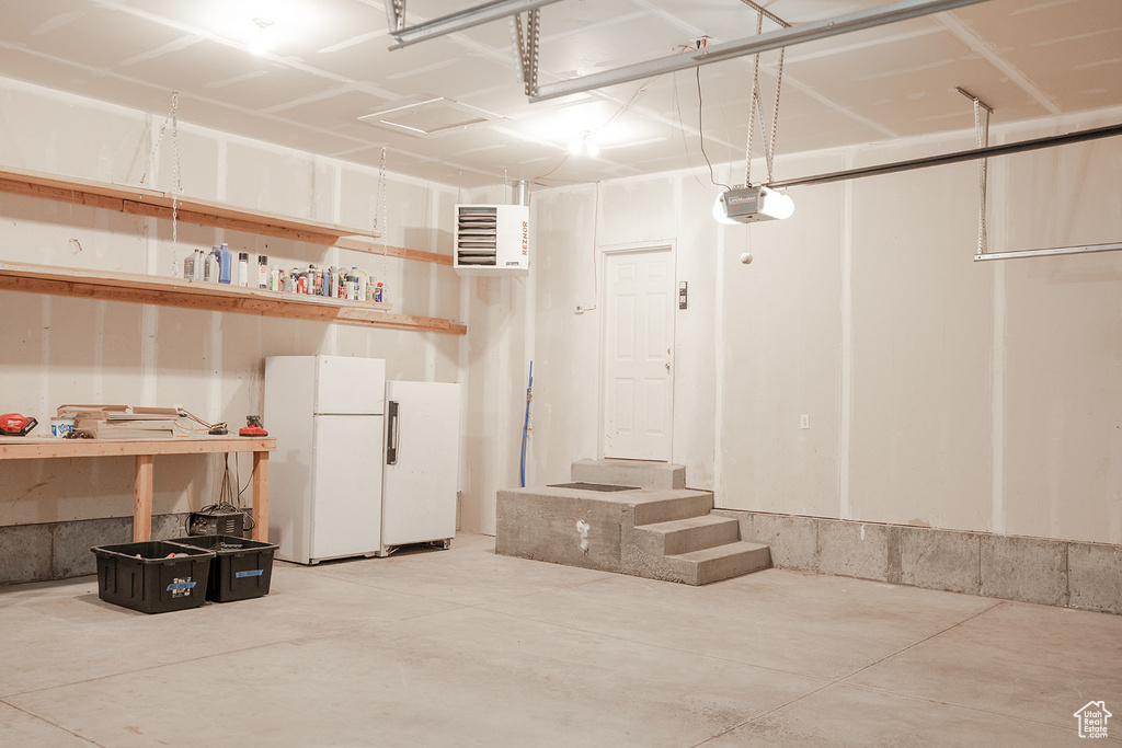 Garage featuring freestanding refrigerator and a garage door opener
