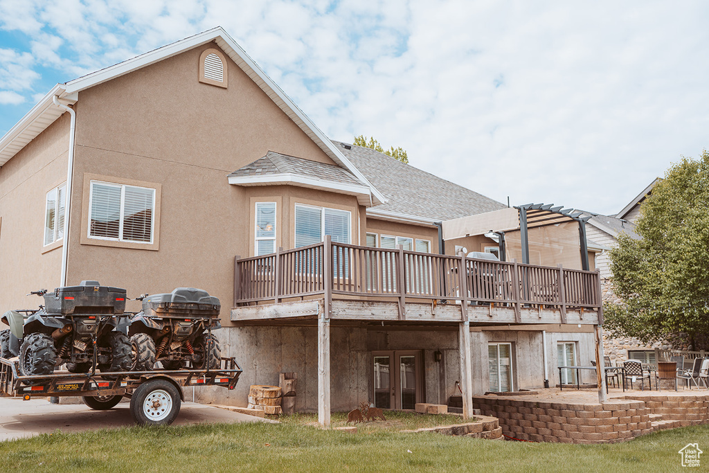 Back of house featuring a wooden deck, a patio area, stucco siding, and french doors