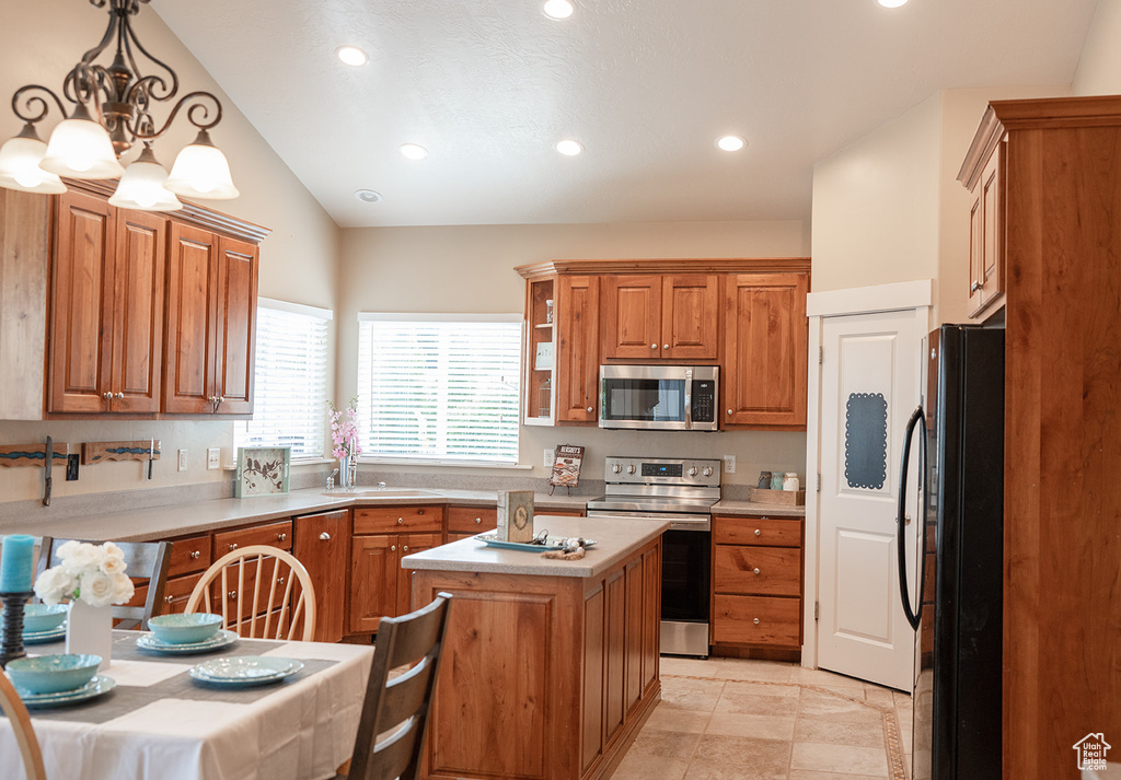 Kitchen featuring appliances with stainless steel finishes, a sink, brown cabinets, lofted ceiling, and light countertops