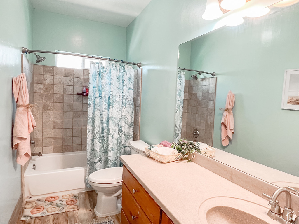 Full bathroom featuring shower / bath combo with shower curtain, toilet, vanity, and wood finished floors