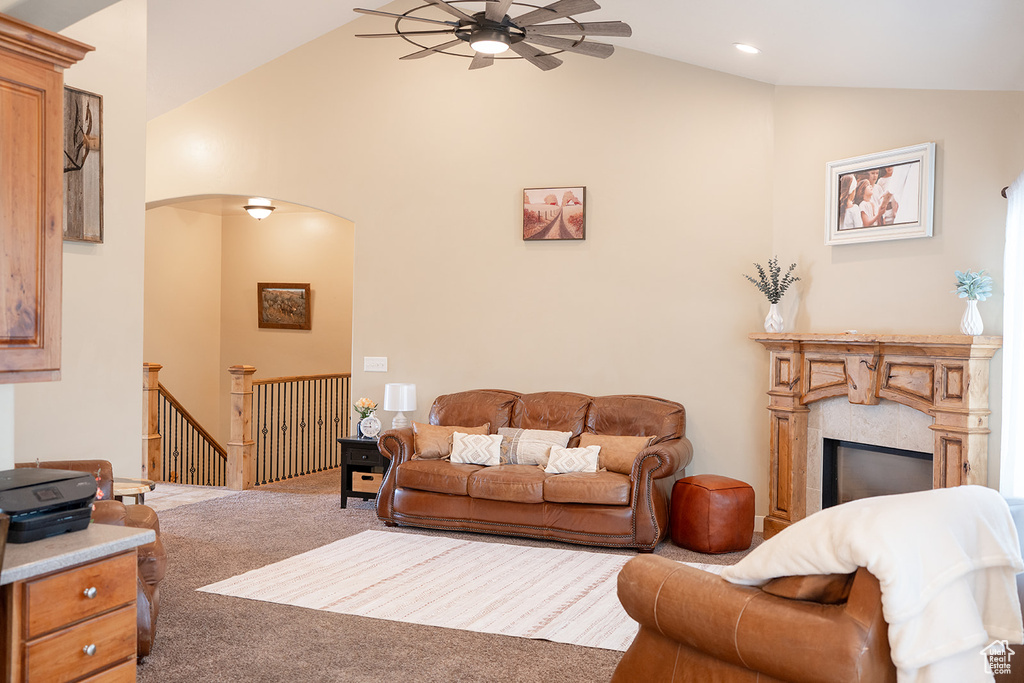Carpeted living room featuring a ceiling fan, lofted ceiling, arched walkways, a fireplace, and recessed lighting