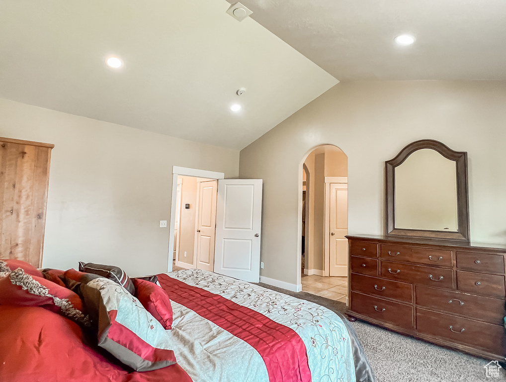 Carpeted bedroom featuring arched walkways, vaulted ceiling, and recessed lighting