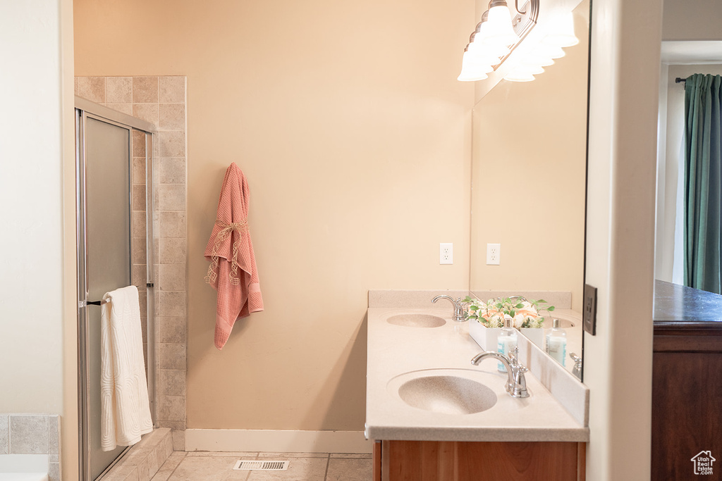 Full bath with a shower stall, double vanity, baseboards, and tile patterned flooring