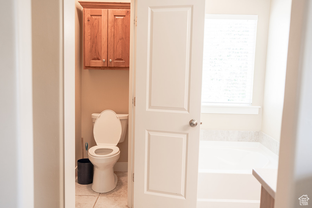 Bathroom featuring a bath, toilet, and tile patterned flooring
