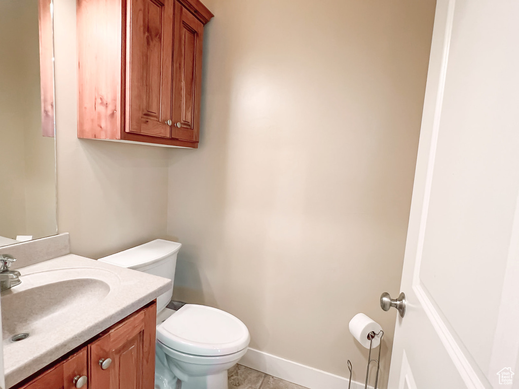Bathroom with toilet, vanity, tile patterned flooring, and baseboards
