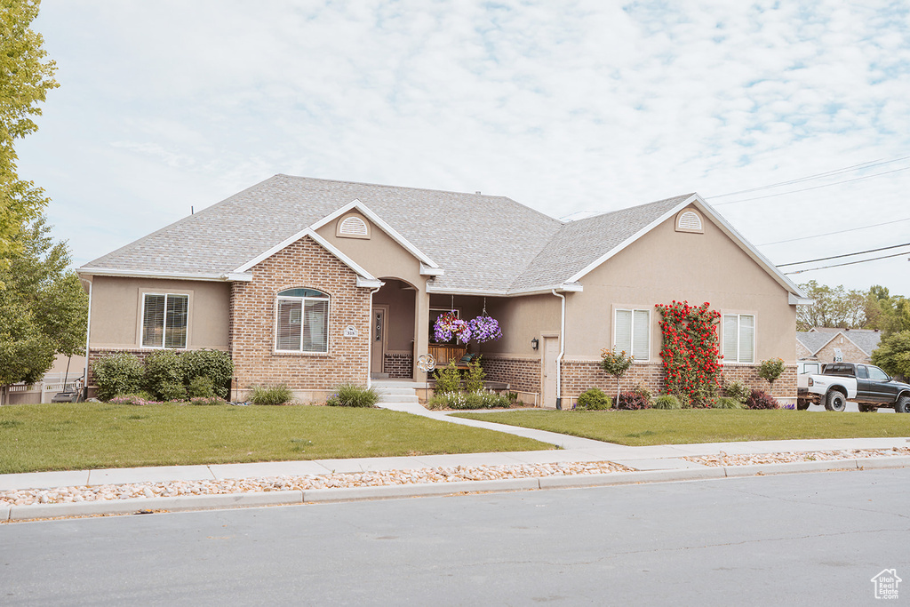 View of front of house featuring stucco siding, brick siding, and a front lawn