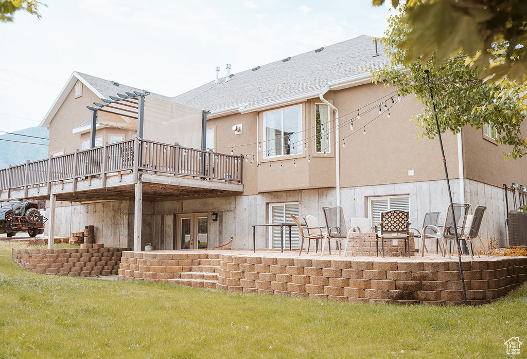 Rear view of house featuring a yard, a patio area, a deck, and stucco siding