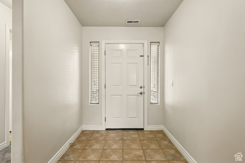 Foyer entrance with baseboards and light tile patterned floors