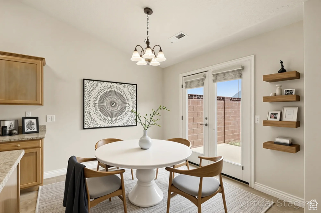 Dining area featuring a chandelier, baseboards, and lofted ceiling