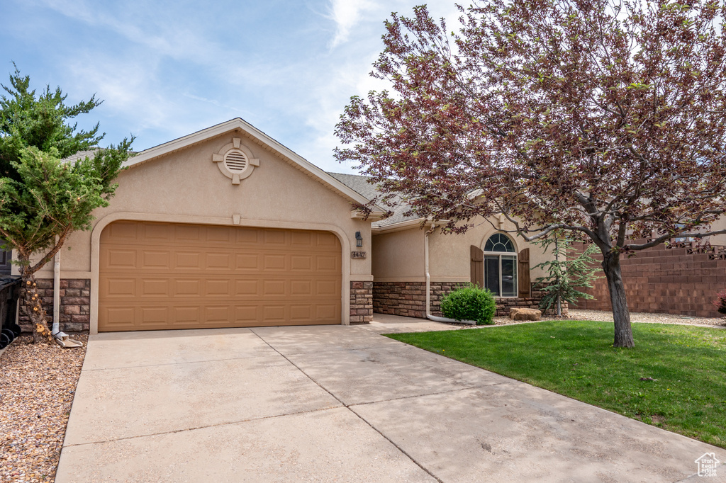 View of front of house featuring stone siding, stucco siding, concrete driveway, and an attached garage