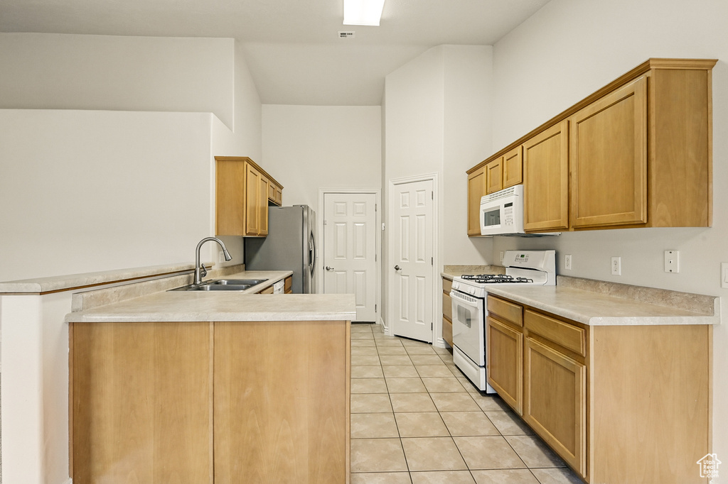 Kitchen featuring white appliances, a sink, a peninsula, light countertops, and a high ceiling