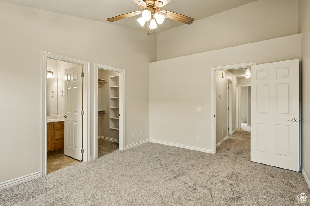 Unfurnished bedroom featuring carpet floors, a spacious closet, baseboards, a closet, and connected bathroom