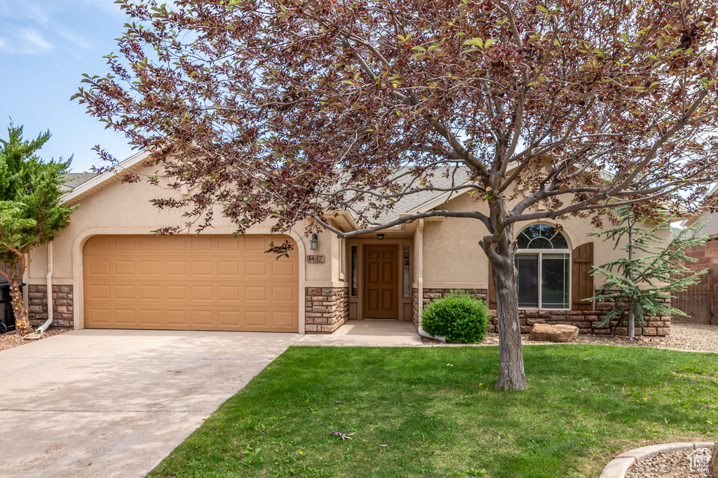 View of front of house featuring stucco siding, stone siding, an attached garage, and driveway