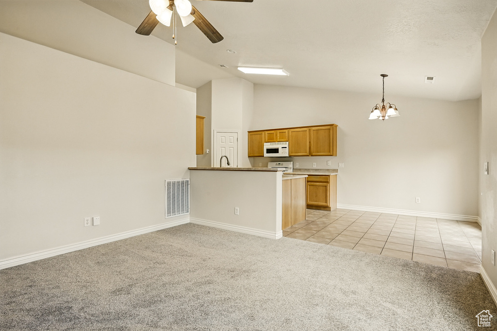 Kitchen featuring white microwave, light colored carpet, a ceiling fan, light tile patterned flooring, and a chandelier