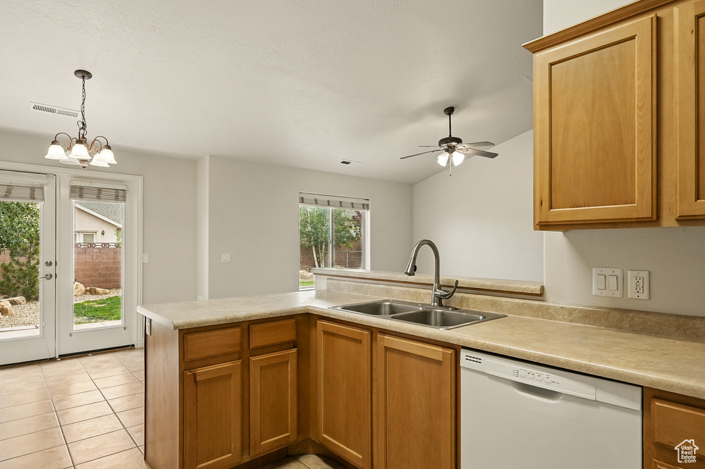 Kitchen featuring white dishwasher, a sink, light countertops, hanging light fixtures, and light tile patterned flooring