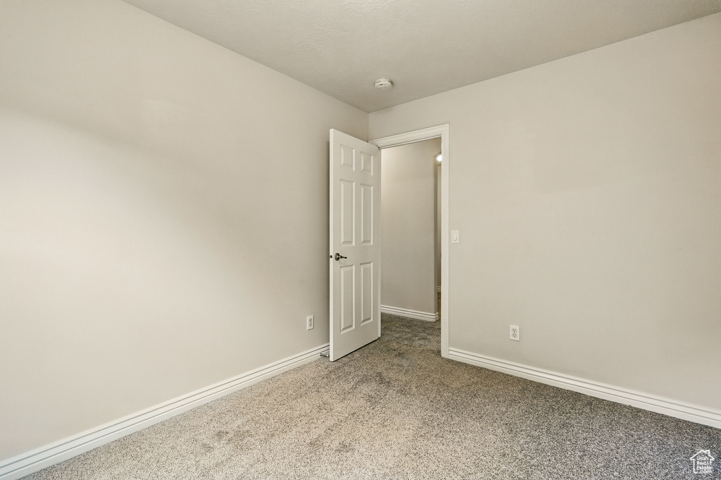 Unfurnished room with carpet floors, baseboards, and a smoke detector