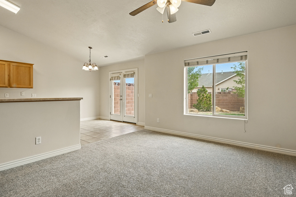 Unfurnished living room featuring light colored carpet, a ceiling fan, light tile patterned flooring, baseboards, and french doors