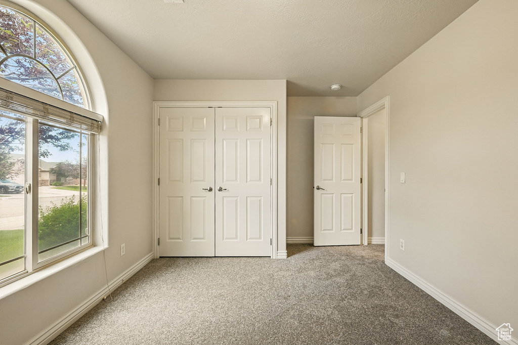 Unfurnished bedroom featuring carpet flooring, a closet, and baseboards