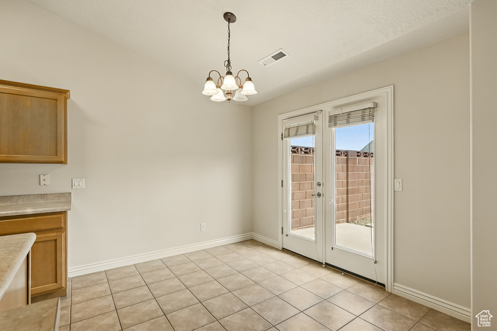 Unfurnished dining area with a chandelier, french doors, baseboards, and light tile patterned floors