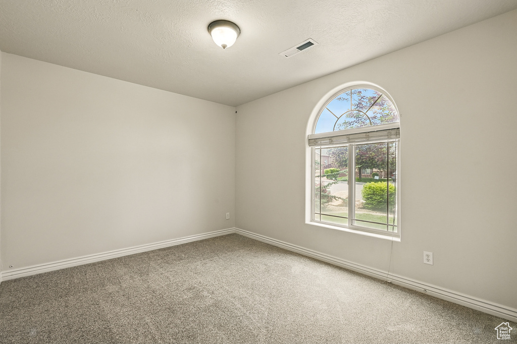 Carpeted spare room featuring baseboards