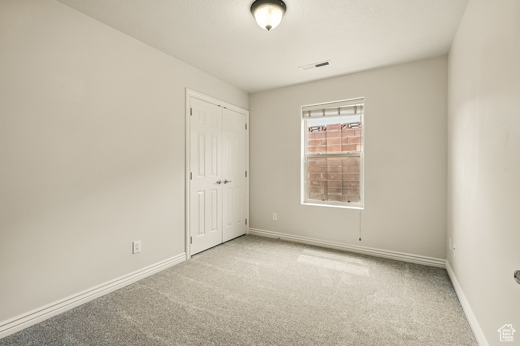 Unfurnished bedroom with carpet floors, baseboards, and a closet