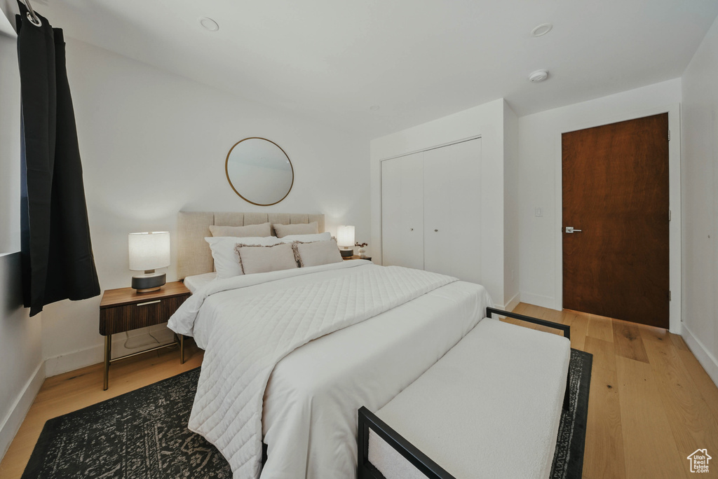 Bedroom featuring light wood-type flooring, baseboards, and a closet