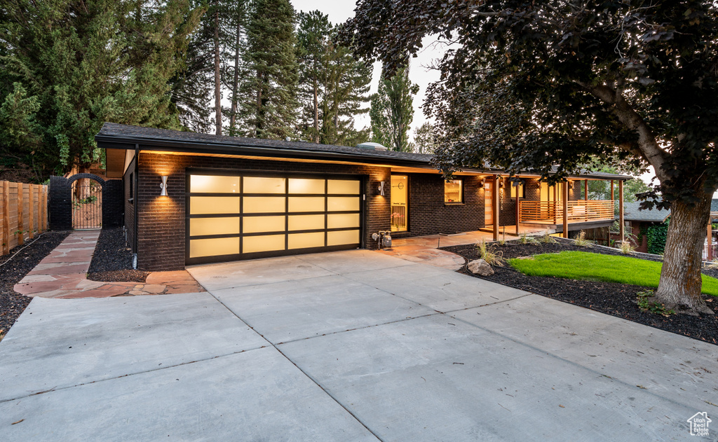 View of front facade featuring a garage, driveway, a gate, and brick siding