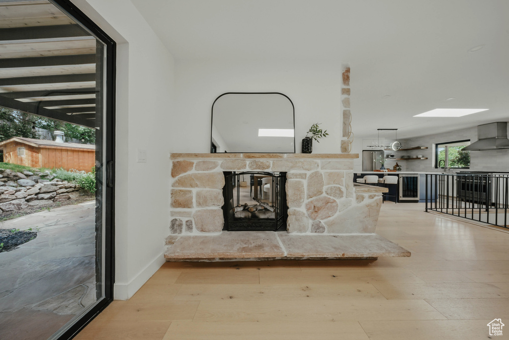 Unfurnished living room with wood finished floors, a fireplace, a sink, and a skylight