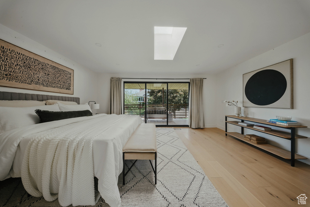 Bedroom featuring a skylight, access to exterior, and light wood-type flooring