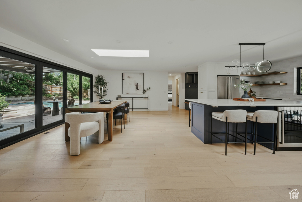 Dining area with wine cooler, light wood-style floors, and a skylight