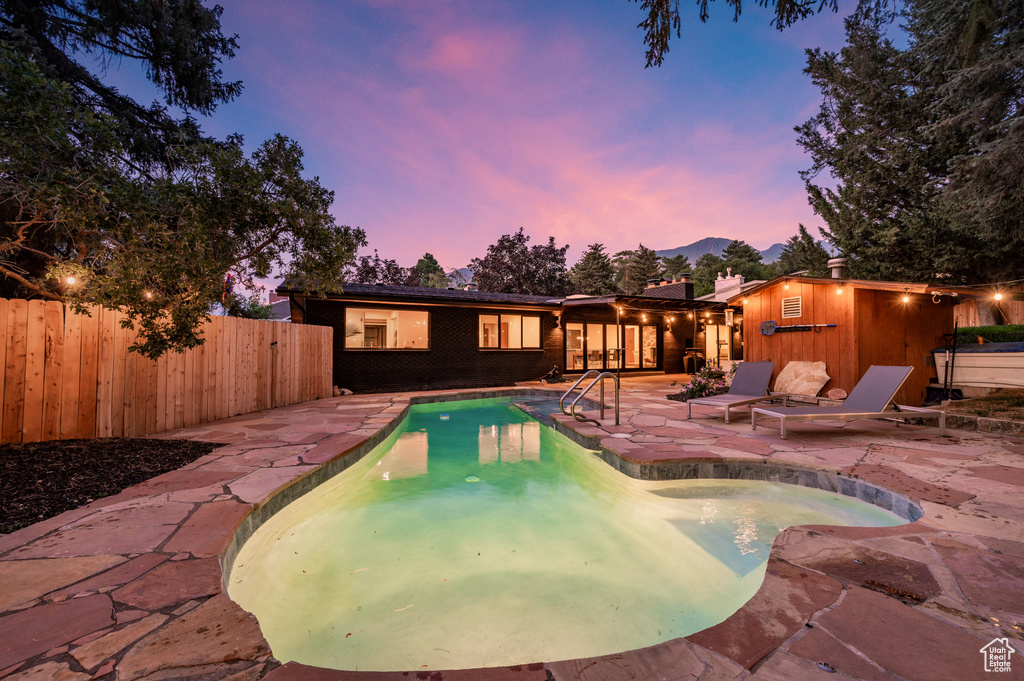 Pool at dusk featuring a patio