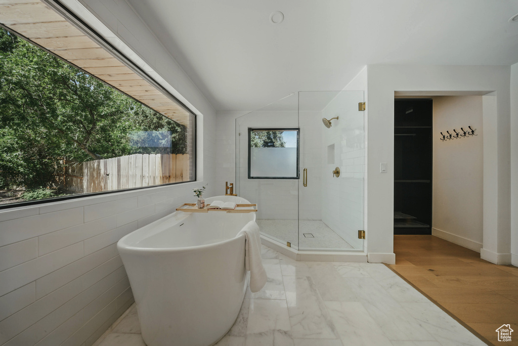 Bathroom with a soaking tub, a shower stall, and tile walls