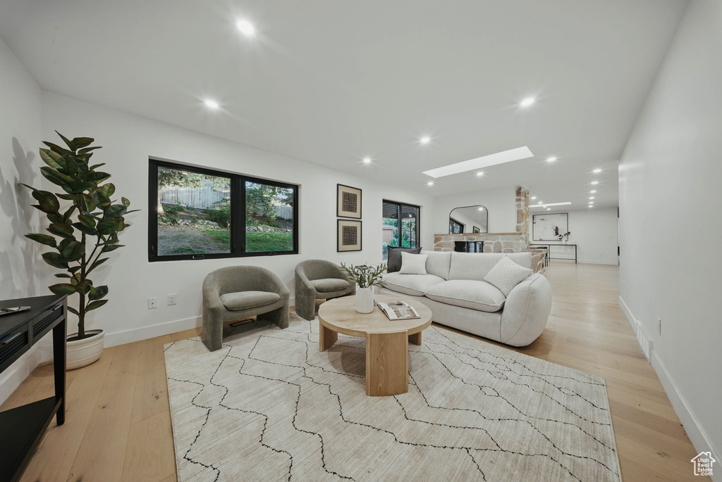 Living area with a skylight, light wood-style flooring, recessed lighting, and baseboards