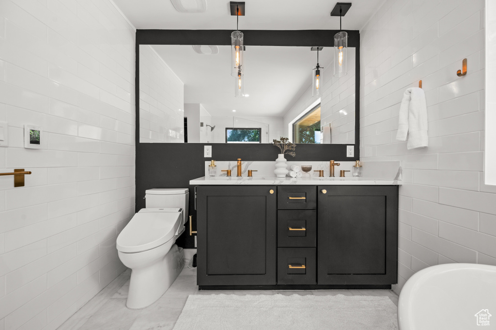 Full bathroom with double vanity, toilet, tile walls, and a freestanding bath