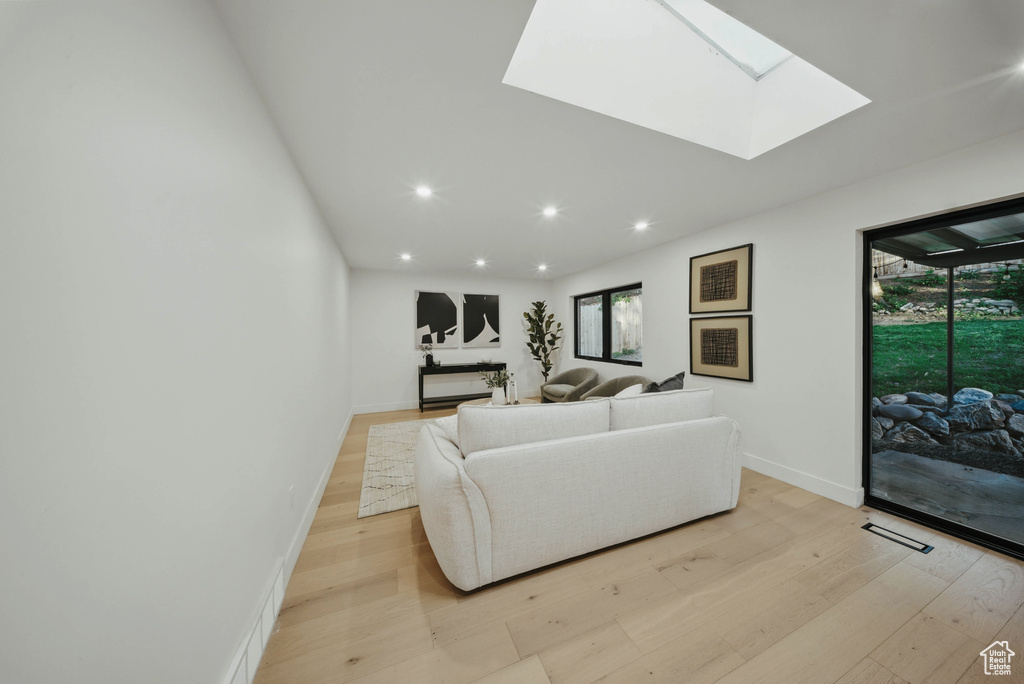 Living room with light wood-style floors, recessed lighting, baseboards, and a skylight