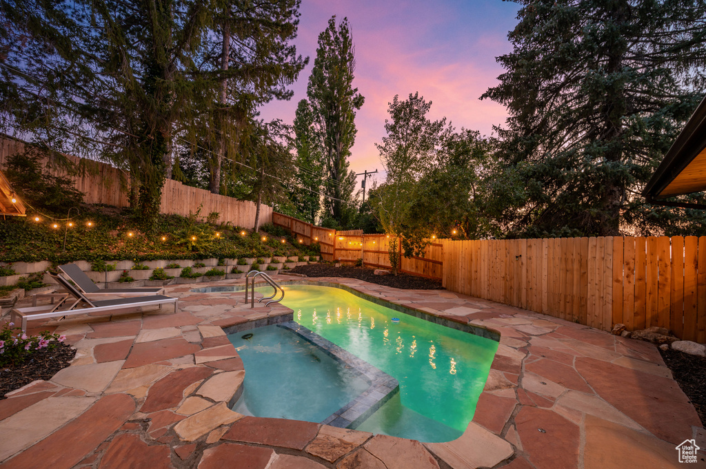 View of swimming pool featuring a pool with connected hot tub, a fenced backyard, and a patio area