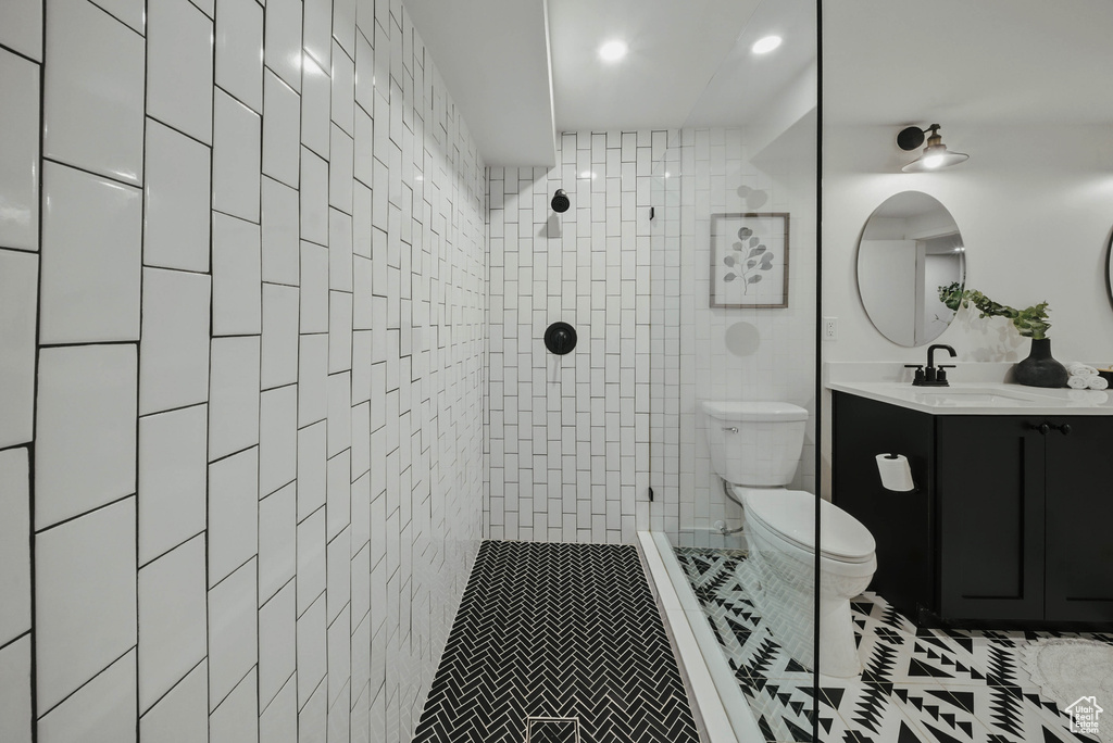 Bathroom with toilet, vanity, a tile shower, tile patterned floors, and recessed lighting