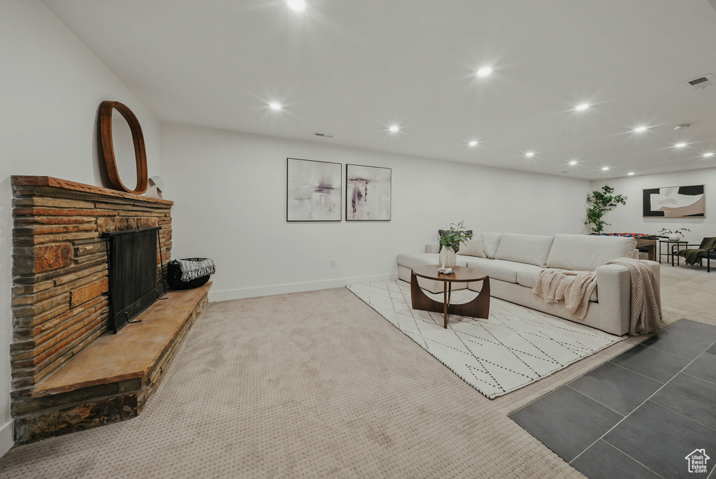 Living room featuring a fireplace with raised hearth, recessed lighting, light colored carpet, and baseboards