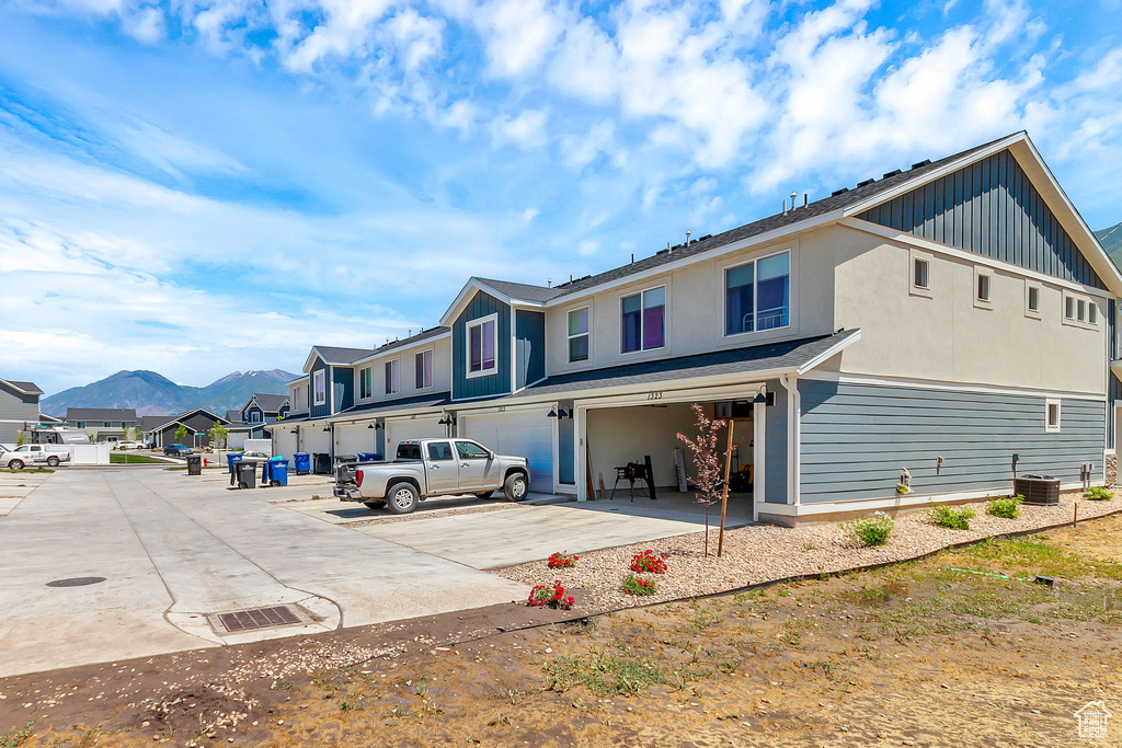 Rear view of house with a garage, a residential view, concrete driveway, board and batten siding, and central AC unit