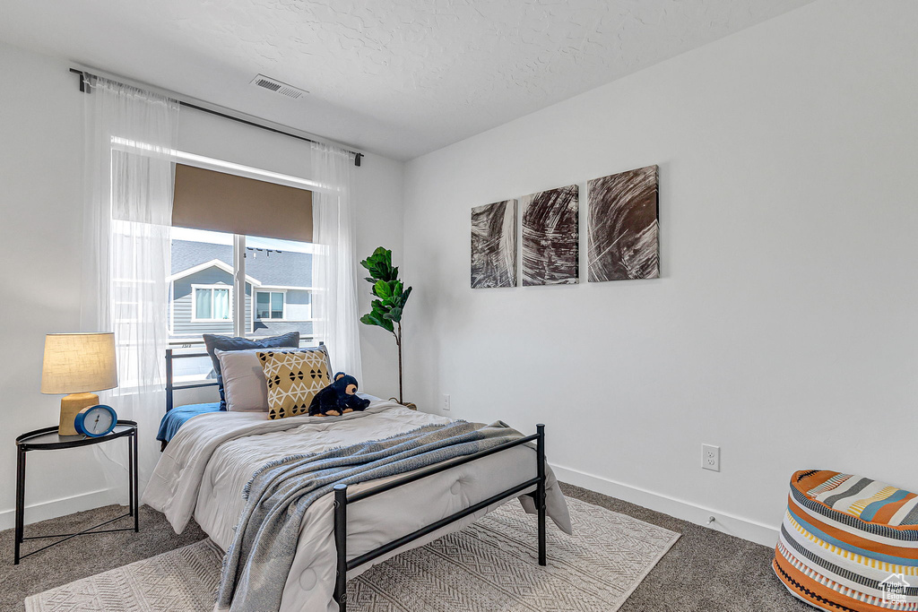Bedroom featuring carpet floors, baseboards, and a textured ceiling