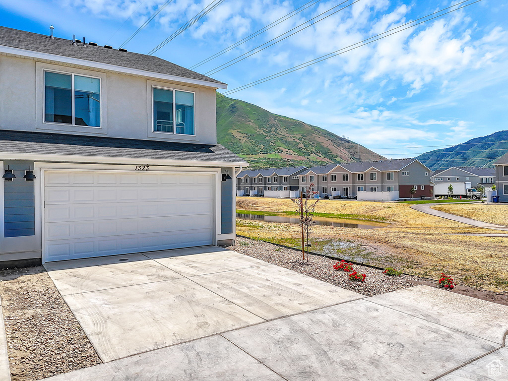 View of property exterior featuring a mountain view, stucco siding, a residential view, driveway, and a garage