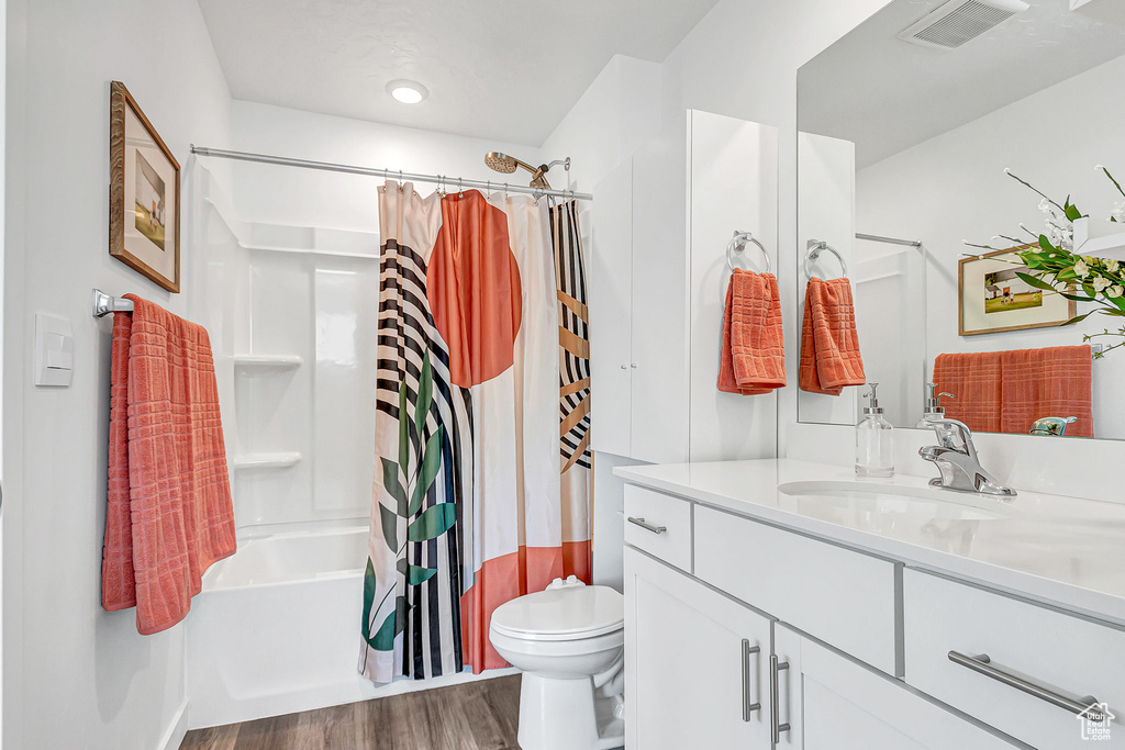 Full bath with wood finished floors, vanity, toilet, and shower / bath combo