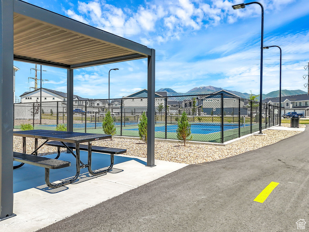 Surrounding community with a tennis court and a mountain view